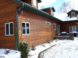 Exterior of home with wood siding and green gutter system after snowstorm
